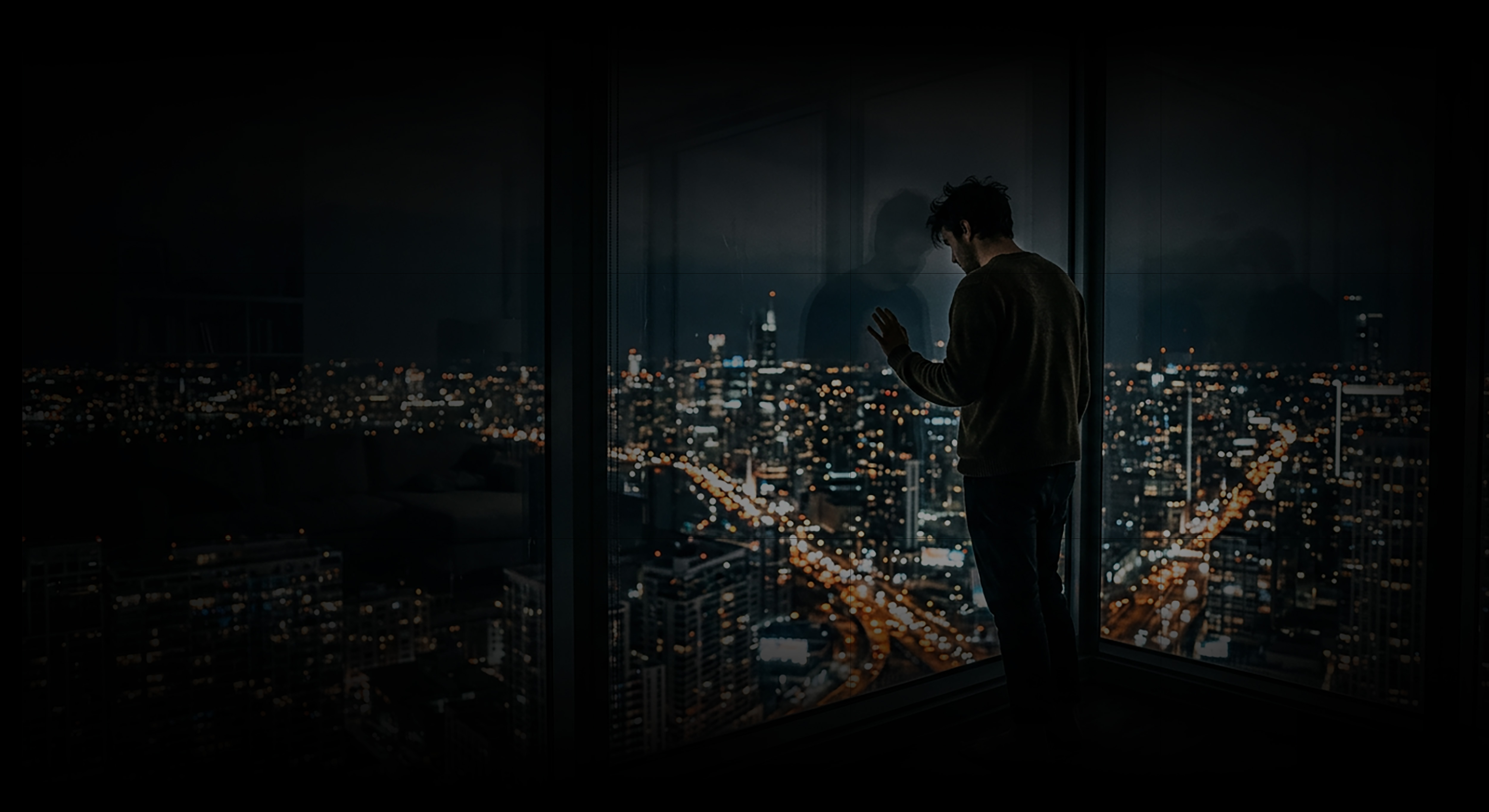 Man Looking Out Large Windows High Above A Sprawling City